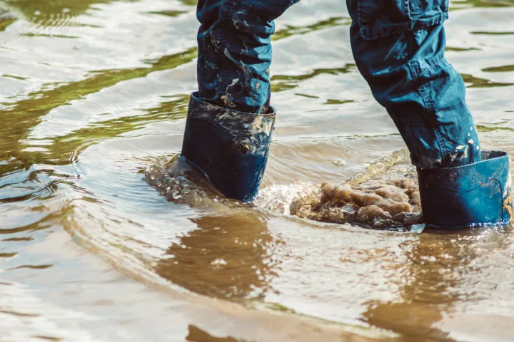 Person steht mit Gummistiefeln in Hochwasser