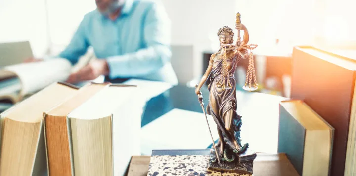 Statue der Justitia auf Büchern und Gesetzbüchern - Symbol für Recht und Gerechtigkeit