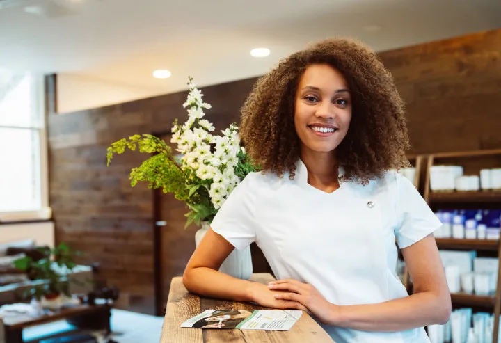 Frau steht an einer Rezeption eines Hotels und lächelt