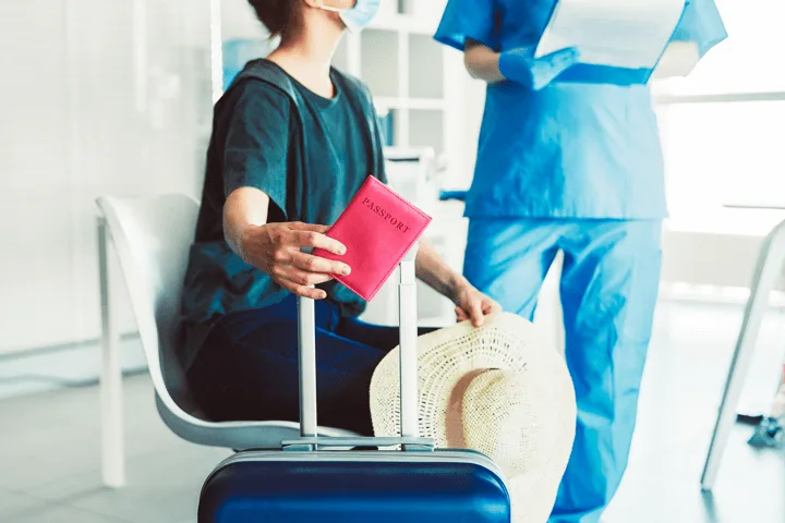 Eine Frau sitzt mit Ihrem Gepäck und Reisepass im Krankenhaus und erhält sich mit dem Personal