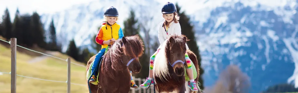 Zwei Kinder reiten auf Ponys