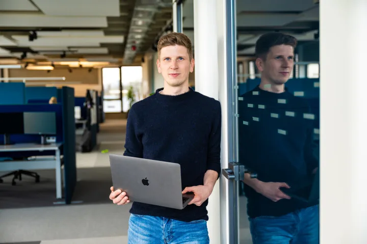 Mann steht im Türrahmen mit Laptop in der Hand